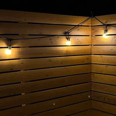 some lights that are on the side of a wooden wall