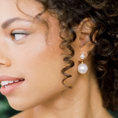 a close up of a woman with curly hair and earrings on her head, looking off to the side