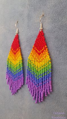 a pair of colorful beaded earrings on top of a gray surface with white beads