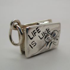 "This three-dimensional, moveable, antiqued sterling silver Box Of Chocolates charm is minted with the phrase \"Life is like\" on the front, and the phrase \"A box of chocolates\" on the reverse. The box opens to reveal two pieces of chocolate, one round and one square. Made by Brown County Silver. Vintage but in brand new, never worn condition. Length 5/8\" length Weight 4.9 grams See more @ https://www.etsy.com/shop/brocosi" Antique Silver Sterling Silver Charms For Gifts, Vintage Nickel-free Charms For Gifts, Vintage Sterling Silver Charms For Gifts, Unique Silver Charms For Gifts, Sterling Silver Charms With Hallmark For Gift, Vintage Silver Charms For Gifts, Vintage Silver Charms For Gift, Meaningful Silver Rectangular Jewelry, Spiritual Silver Charms For Gifts