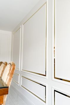 a dining room table and chairs in front of white walls with gold trimmings