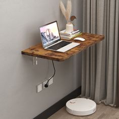 a laptop computer sitting on top of a wooden shelf next to a window with curtains