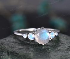 - Metal: Solid gold(10K/14K/18K white/yellow/rose gold),925 sterling silver,platinum available- Main Stone: 7mm round cut natural blue Labradorite- Accent Stone: 3mm and 2mm round moonstones- Can be personalized: Yes Elegant Three-stone Moonstone Ring For Gift, Oval Three Stone Moonstone Ring For Anniversary, Three Stone Round Moonstone Ring Gift, Three Stone Moonstone Ring Gift, Dainty Round Moonstone Ring For Anniversary, Wedding Moonstone Ring With Bezel Setting, Round Moonstone Wedding Ring With Bezel Setting, Minimalist Moonstone Wedding Ring, Engagement Ring Moonstone