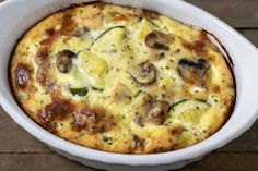 a casserole with mushrooms and zucchini in a white dish on a wooden table