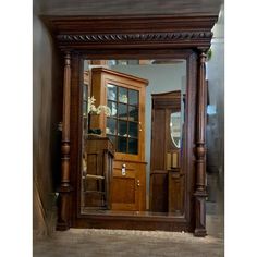 a large mirror sitting on top of a wooden floor next to a wall mounted cabinet