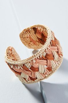 a close up of a woven bracelet on a white surface with an object in the background