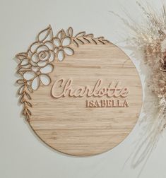 a wooden sign that says charlotte is available on the wall next to some dried flowers