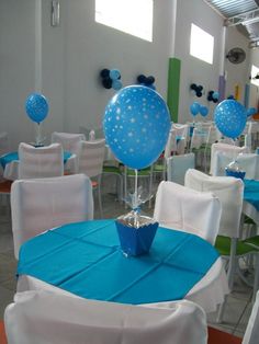 a room filled with tables and chairs covered in blue and white tablecloths topped with balloons