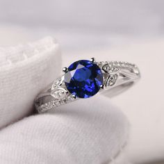 a blue stone ring sitting on top of a white cloth