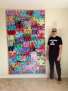 a man standing in front of a large piece of art with words written all over it