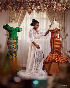 a woman standing next to two mannequins in front of a flower covered window