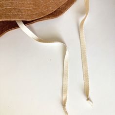 a brown hat with a white ribbon around it's neck on a white surface