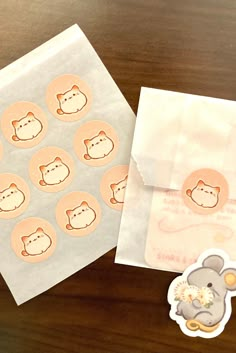 an envelope with some stickers on it next to a paper bag filled with small round stickers