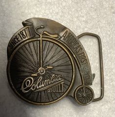 This vintage belt buckle is a must-have for any collector or fan of cycling. Featuring a solid pattern and brass plating, this piece from Bergamot Brass Works is a true vintage item from the 1970s. Measuring 2.40"(w) x 2.50"(h) and fitting belts up to 1.90" in width, it is perfect for both men and women.  The unique TF05112 ID confirms the authenticity of this classic piece, which celebrates the history of the Columbia bicycle brand. Made in the United States, this belt buckle is a great additio Vintage Adjustable Belt Buckles With Brass Buckle, Vintage Gold Belt Buckles For Collectors, Vintage Brass Buckle Belt Buckles Collectible, Bicycle Brands, Vintage Belt Buckles, Vintage Belt, Suspender Belt, San Antonio Tx, Solid Pattern