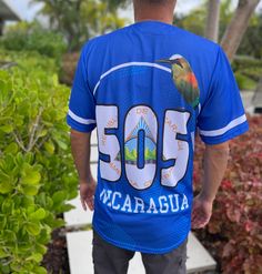 Nicaragua Baseball Jersey in classic blue. This short-sleeve, button-up jersey features high-quality sublimation printing of the Nicaraguan coat of arms on the front, a proudly displayed flag on the sleeve, and the iconic "505" on the back, symbolizing Nicaragua’s roots. Sublimated Coat of Arms Design: Showcases Nicaragua's heritage with vibrant detail. Iconic "505" on Back: Represents Nicaragua’s international calling code. Flag Patch on Sleeve: Adds an authentic touch of national pride. Comfor Blue Short Sleeve T-shirt For Outdoor, Blue Graphic Print Top For Outdoor, Blue T-shirt With Letter Print For Outdoor, Casual Blue Short Sleeve Shirt With Graphic Print, Outdoor Blue T-shirt With Letter Print, Casual Blue Shirt With Sublimation Print, Printed Light Blue Short Sleeve T-shirt, Blue Printed Shirt For Streetwear, Blue Custom Print Shirt For Streetwear