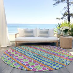 a living room with a couch and rug on the floor next to an ocean view