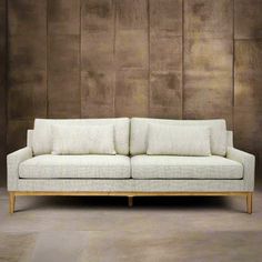 a white couch sitting on top of a cement floor next to a wooden frame wall