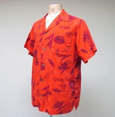 * Men's Hawaiian shirt c 1960s* Cotton fabric* Anthurium, Bird of Paradise, shields, and other tropical motifs in maroon on red background* Small spread collar * Single patch pocket* Back yoke has action pleats for comfort* Short, set-in sleeves are notched at hem* 5 coconut shell buttons* Squared-off hem with 2" side ventsMissing labelVery good condition. One minor repair has been made. A pinhole above the breast pocket was repaired by fusing fabric from inner seam. Virtually impossible to dete Tropical Motifs, Surfer Shirt, Surfer Print, Floral Tee, Bird Of Paradise, Silk Jacket, Shell Buttons, Puff Sleeve Blouse, Coconut Shell