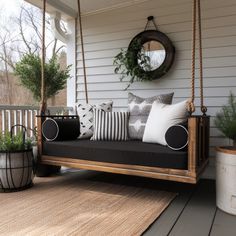 a porch swing with pillows and plants on it