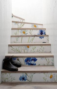 a pair of black shoes sitting on top of a set of stairs with flowers painted on it