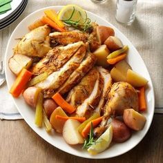 a white plate topped with chicken, potatoes and carrots on top of a wooden table