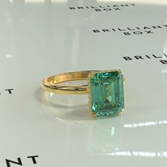 an emerald colored ring sitting on top of a table