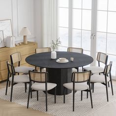 a round table with six chairs around it in front of a large window and wooden dresser