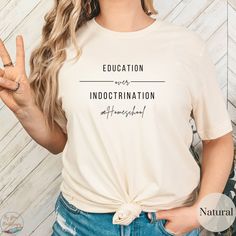 a woman wearing a white t - shirt with the words education and an image of her fingers up