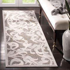 a white and gray rug in front of a door with a plant next to it