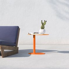 a chair and table with a potted cactus on it in front of a white wall