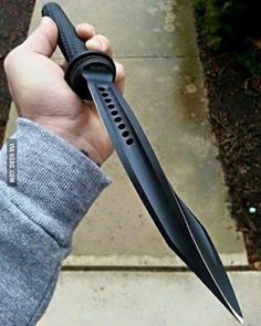 a hand holding a large black knife on top of it's side with its blade out