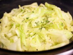 a bowl filled with cabbage and seasoning sitting on top of a stove burner