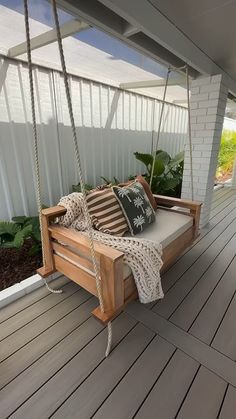 a wooden porch swing with pillows on it