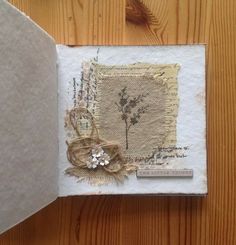 an open book on a wooden table with paper and fabric around the pages, decorated with flowers