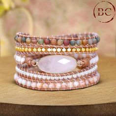 Elevate your boho jewelry collection with this exclusive women's rose quartz charm 5-layer beads wrap bracelet. This exquisite piece features multiple layers of high-quality leather, meticulously adorned with delicate rose quartz beads and charms, creating a stunning blend of natural beauty and bohemian flair. The bracelet showcases five layers of leather, each intricately wrapped with smooth rose quartz beads. Known for their gentle pink hue and calming energy, the rose quartz stones add a touch of elegance and serenity to the bracelet. The addition of charming rose quartz accents or detailed charms further enhances the bracelet's overall design, infusing it with a unique and sophisticated appeal. Handcrafted with precision, this multilayered bracelet wraps comfortably around the wrist, o Bohemian Rose Quartz Beaded Bracelets With Adjustable Fit, Bohemian Rose Quartz Adjustable Beaded Bracelets, Bohemian Adjustable Rose Quartz Beaded Bracelets, Bohemian Hand Wrapped Rose Quartz Bracelets, Bohemian Beaded Bracelets With Rose Quartz, Bohemian Hand-wrapped Rose Quartz Beaded Bracelets, Bohemian Hand Wrapped Rose Quartz Beaded Bracelets, Beadwork Bracelet, Beaded Wrap Bracelets