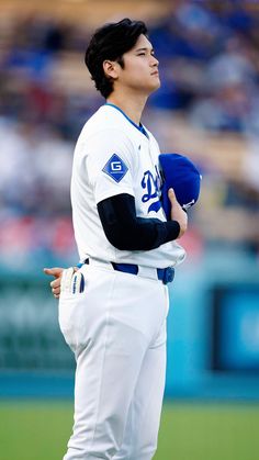 a baseball player standing on top of a field holding a blue ball in his hand