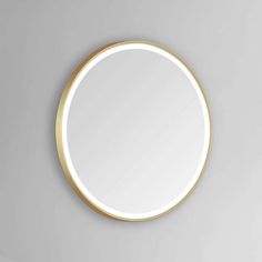 a round mirror on the wall with a gold rim and white light reflecting in it