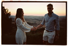 a man and woman holding hands while standing on top of a hill at sunset or sunrise