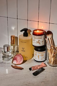 various beauty products are sitting on a marble countertop next to a candle and mirror