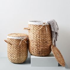 three woven baskets sitting on top of a white shelf next to each other with lids