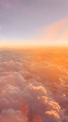 the view from an airplane looking down at clouds and sun in the sky above them