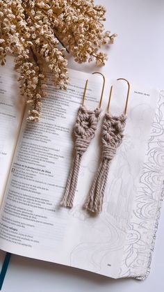 two crocheted bookmarks sitting on top of an open book next to some dried flowers