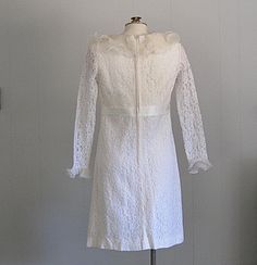 APPROXIMATE MEASUREMENTS (INCHES): Current Size: XS/S Bust: 36 Waist: 30 Hip: 36 Length (shoulder to hem): 38 CONDITION Excellent/very good. There is one small repair to the collar (see photo) DESCRIPTION 1960s / early 1970s dress White lace lined with acetate Sleeves are unlined Collar and cuffs are pleated sheer chiffon Back metal zip closure Fitted Wedding Dress With Lace Cuffs, Vintage White Lace Dress, Wedding Dresses 60s, Clown Dress, Tiki Dress, Betty Dress, 1970s Dress, Vintage Wedding Dress, 1970s Dresses