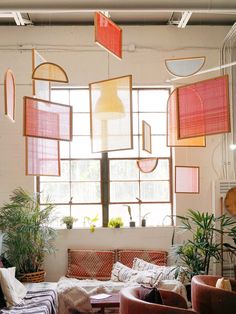 a living room filled with lots of furniture and plants on the windowsill, next to a large window