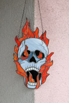 a skull hanging from a chain with flames coming out of it's mouth and eyes