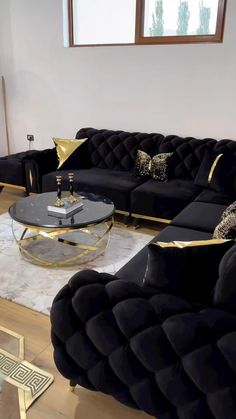 a living room with black couches and gold accents