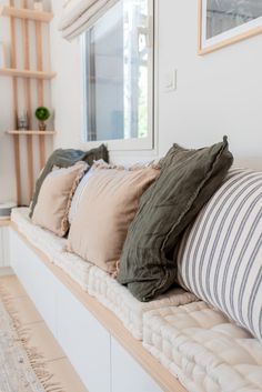 the pillows are lined up on the bench in front of the window sill,