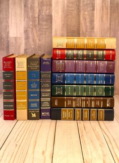 a stack of books sitting on top of a wooden table next to each other in front of a wood paneled wall