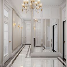 an empty hallway with chandelier and marble flooring on the walls, leading to another room