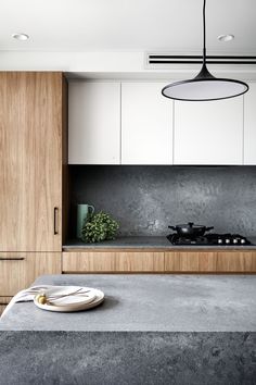 a kitchen with white cabinets and grey countertops, an island in the middle has a plate on it